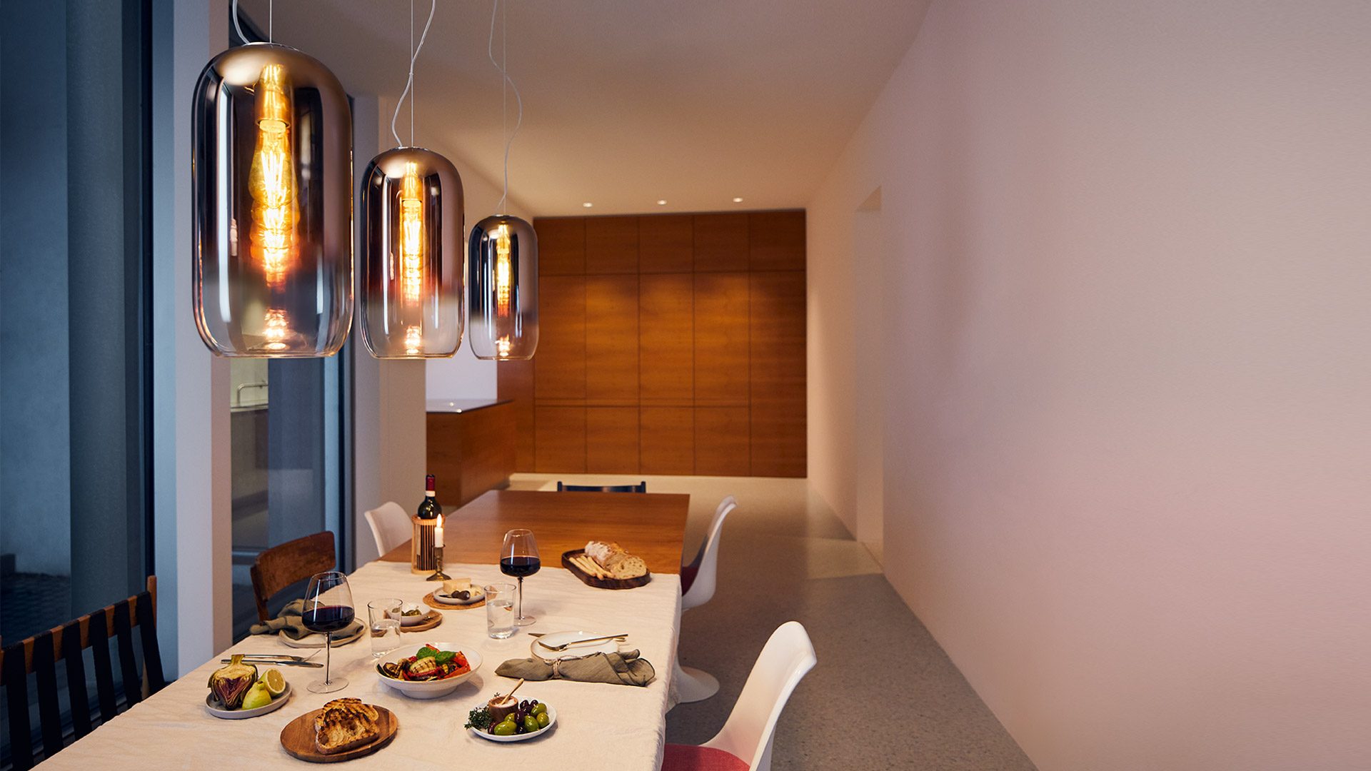 Sala da pranzo con sospensioni Artemide Gople in vetro soffiato: la stessa scena al buio e con la luce accesa