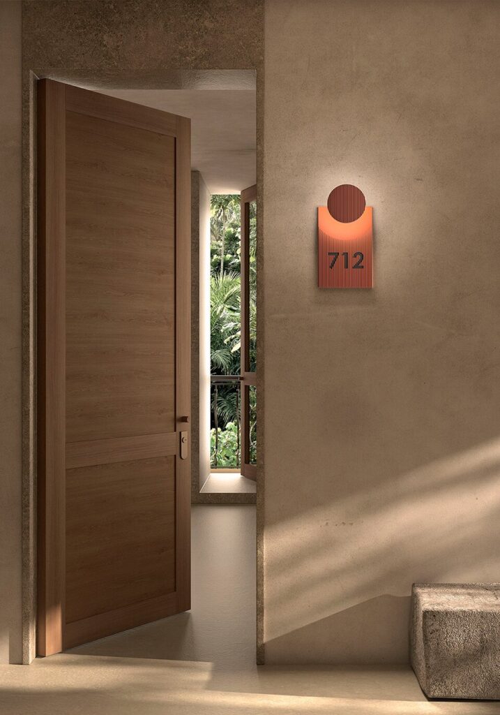 Applique Bover Arid in terracotta accanto a una porta in legno