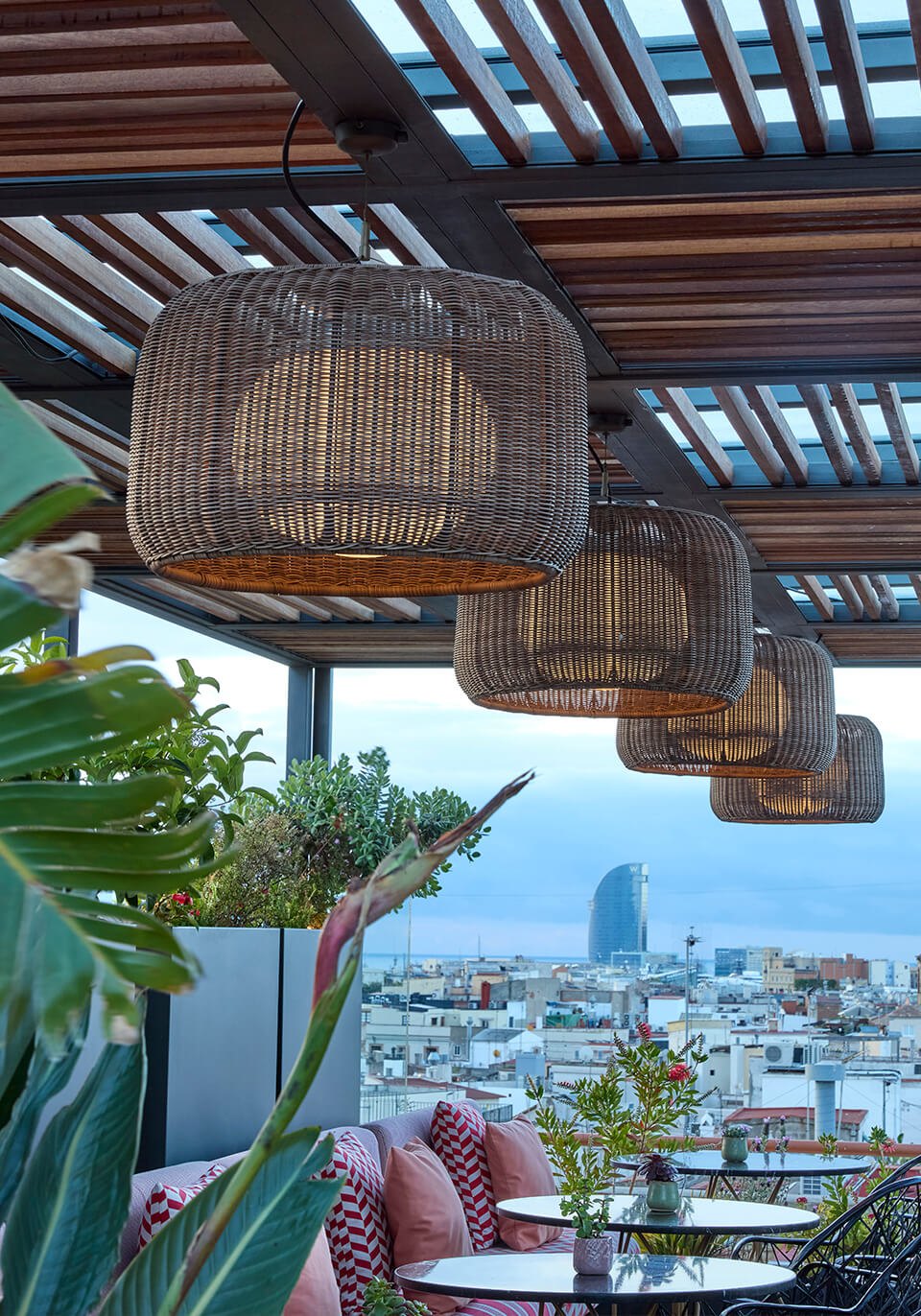 Terrazza con vista su Barcellona e le sospensioni Bover Fora in fibra sotto la pergola: la stessa scena al buio e con la luce accesa