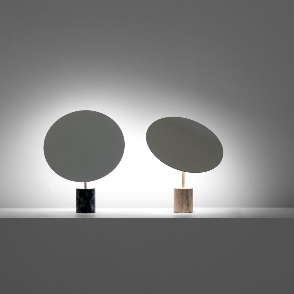 Lampada da tavolo Davide Groppi Calvino con il disco che riflette la luce, su un tavolo di marmo