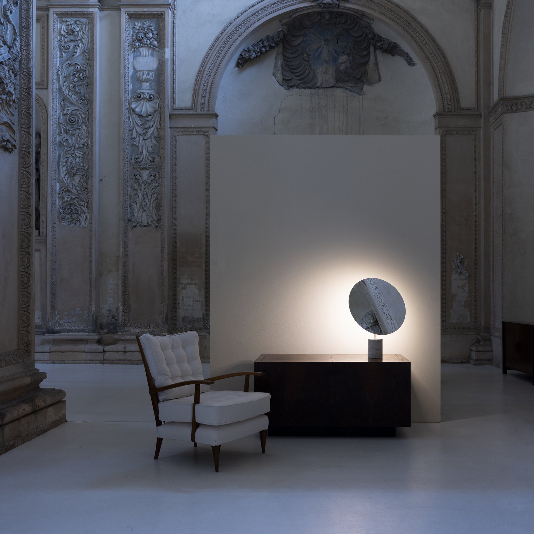 Salone d'epoca al buio con la lampada Davide Groppi Calvino accesa accanto a una poltrona: la stessa scena al buio e con la luce accesa