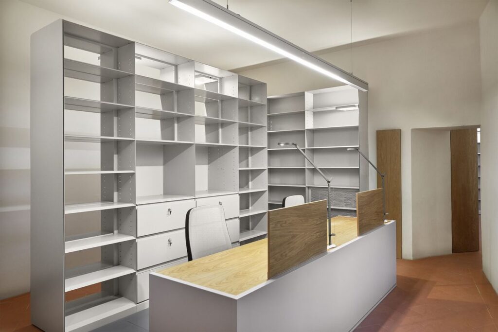 Biblioteca con le applique Exenia Pluriel sulle scaffalature