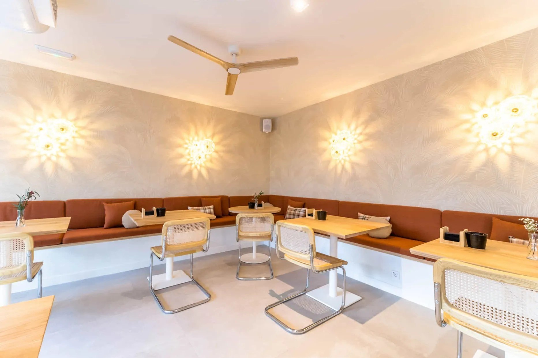 Sala di una caffetteria con le applique a raggiera Faro Barcelona sulle pareti: la stessa scena al buio e con la luce accesa