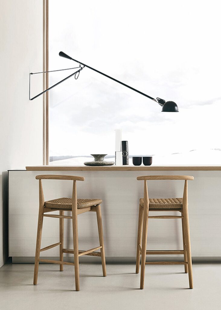 Lampada da parete Flos 265 con il braccio lungo sopra un bancone con gli sgabelli