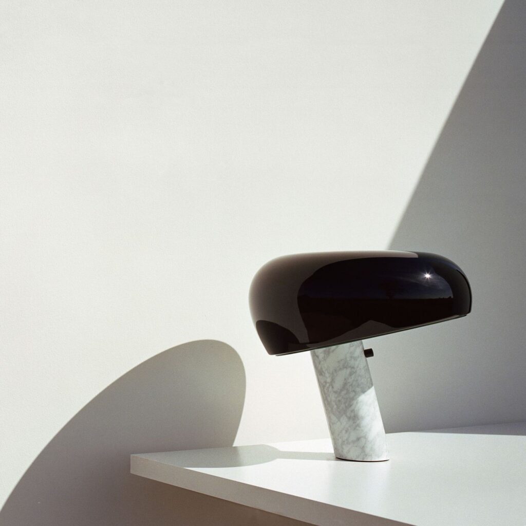 Lampada da tavolo Flos Snoopy con la base in marmo e il cappello nero su una mensola bianca