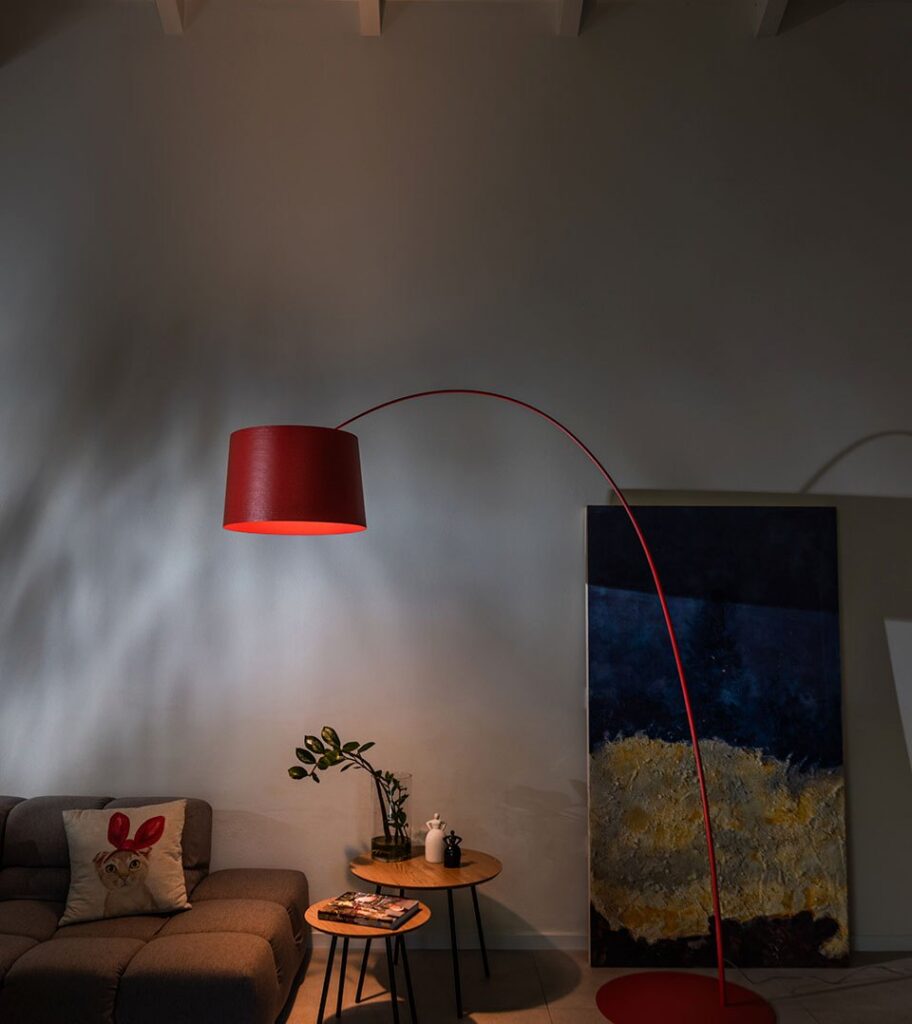 Lampada da terra Foscarini Twiggy rossa con l'arco sopra un divano