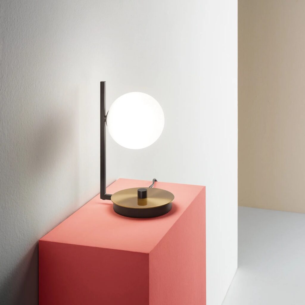 Lampada da tavolo Ideal Lux Birds con la sfera di vetro su un mobile rosso