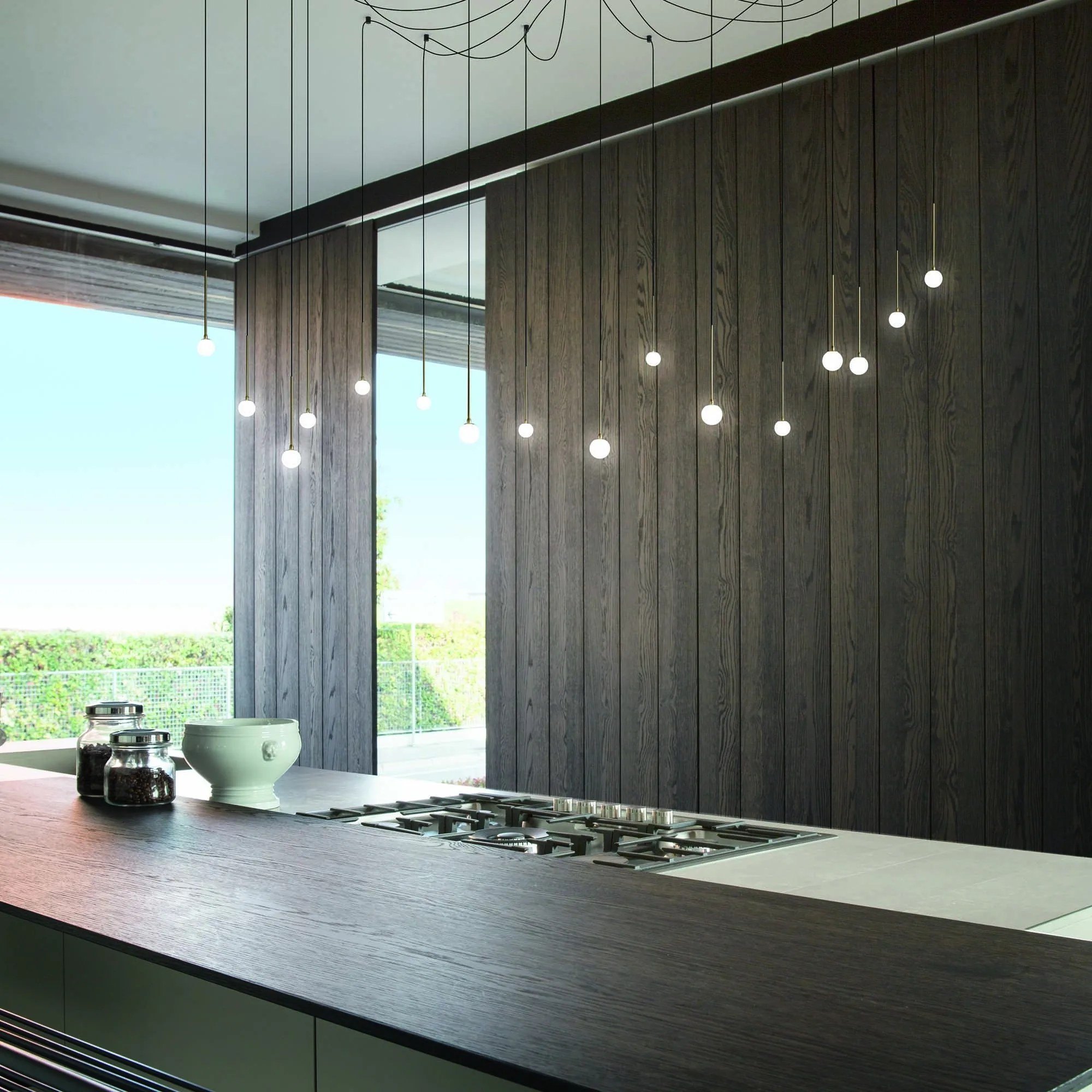 Cucina moderna di sera con le lampade Ideal Lux Lucciola sospese sopra il piano: la stessa scena al buio e con la luce accesa