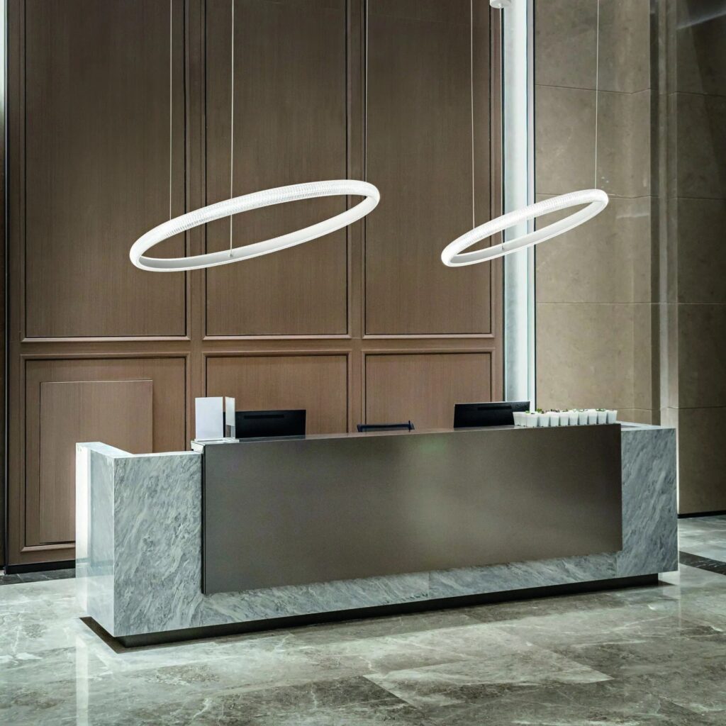 Reception con gli anelli di luce Ideal Lux Miracle sospesi sopra il banco in marmo