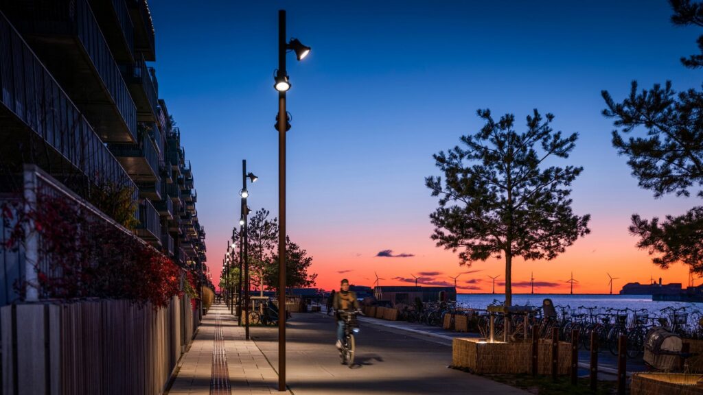Lungomare al tramonto con i proiettori iGuzzini Woody sugli alberi