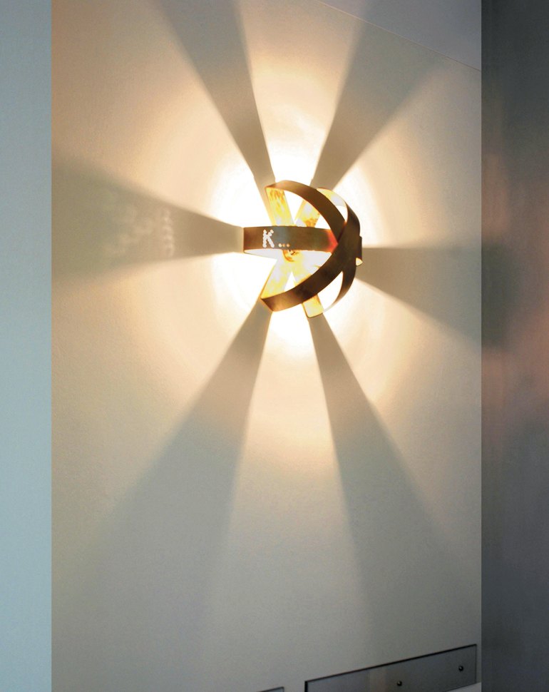 Applique Knikerboker Ecliptika con la luce che esce a raggiera dal metallo