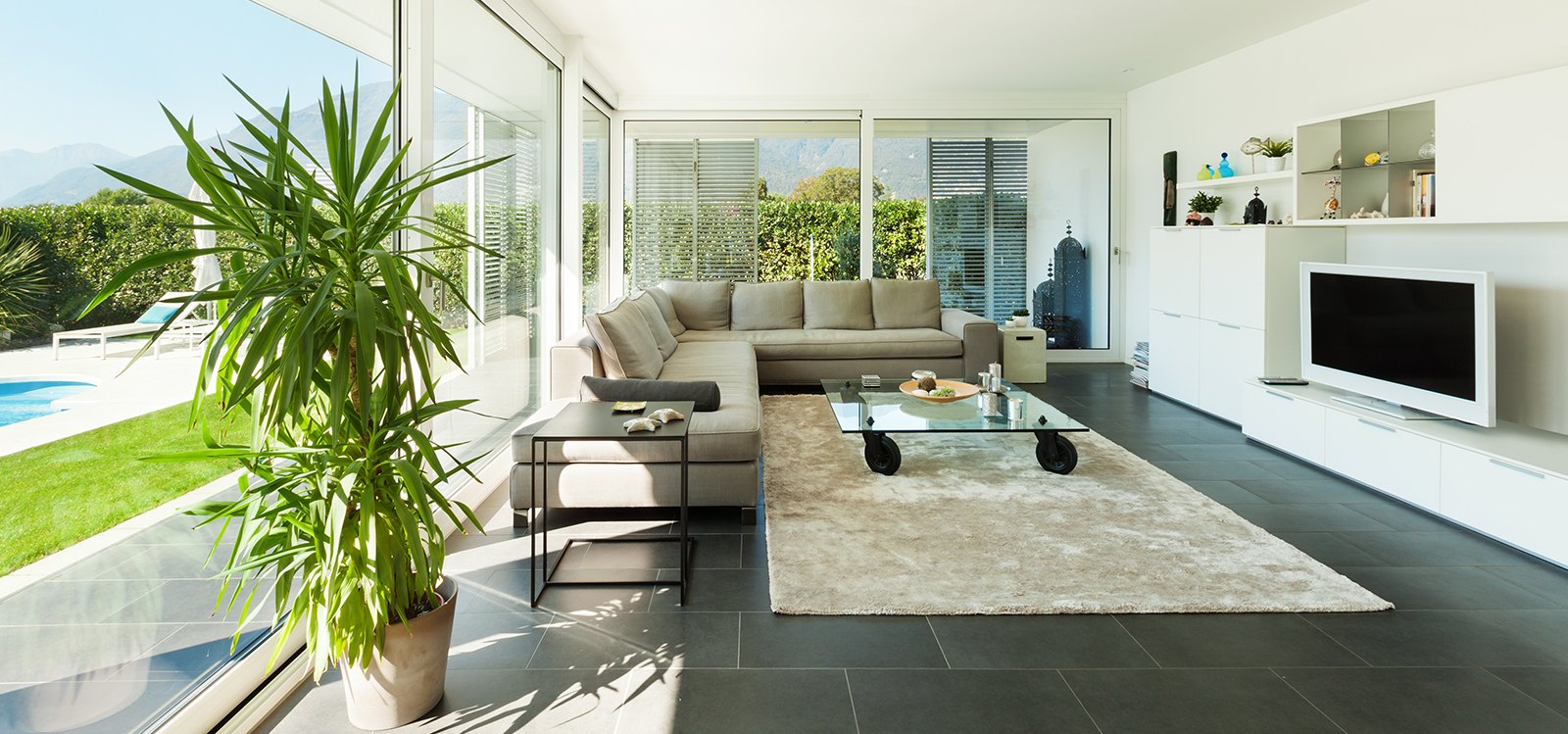 Soggiorno con le vetrate sul giardino e la piscina: la stessa scena al buio e con la luce accesa dalla domotica