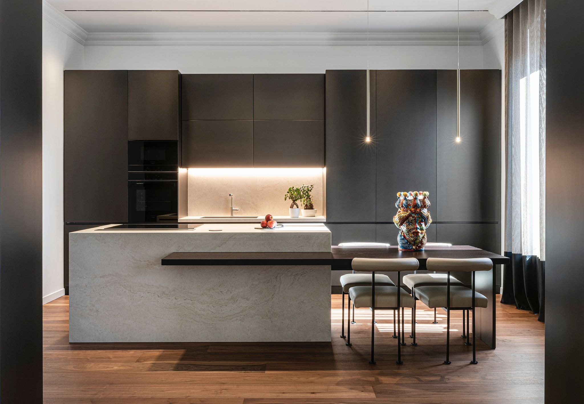 Cucina scura con il tavolo illuminato dalle sospensioni Lip Lighting: la stessa scena al buio e con la luce accesa