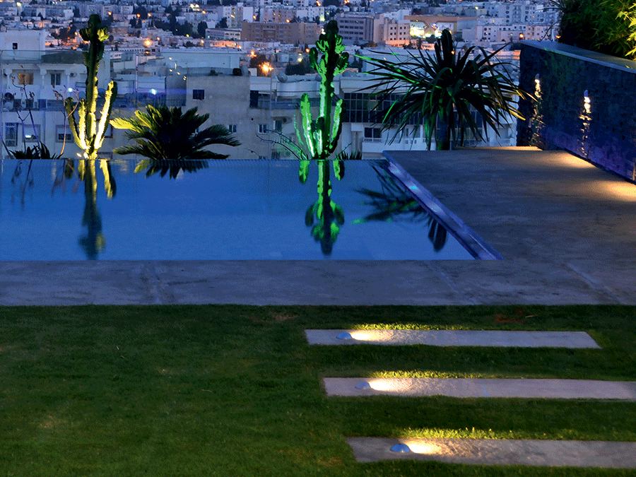 Piscina con le palme illuminate dai proiettori Luce&Light Beam: la stessa scena al buio e con la luce accesa