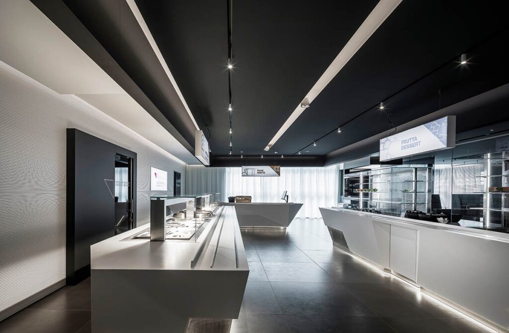 Negozio con il binario Macrolux Dark a soffitto e le linee di luce, con il bancone al centro