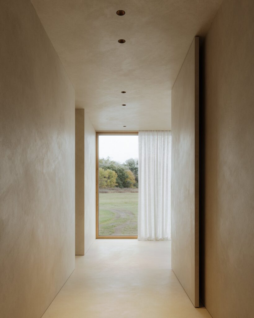Corridoio con gli incassi Modular Klevr a soffitto e la porta aperta sul verde