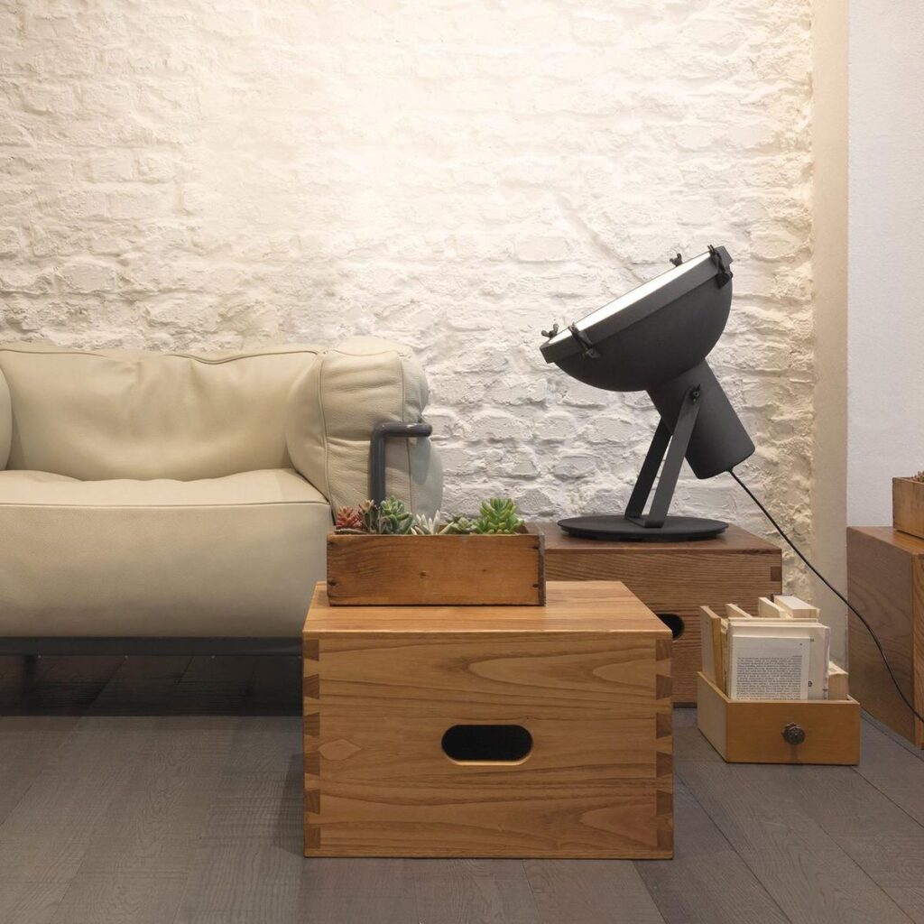 Lampada Nemo Projecteur 365 su una cassa di legno accanto a un divano