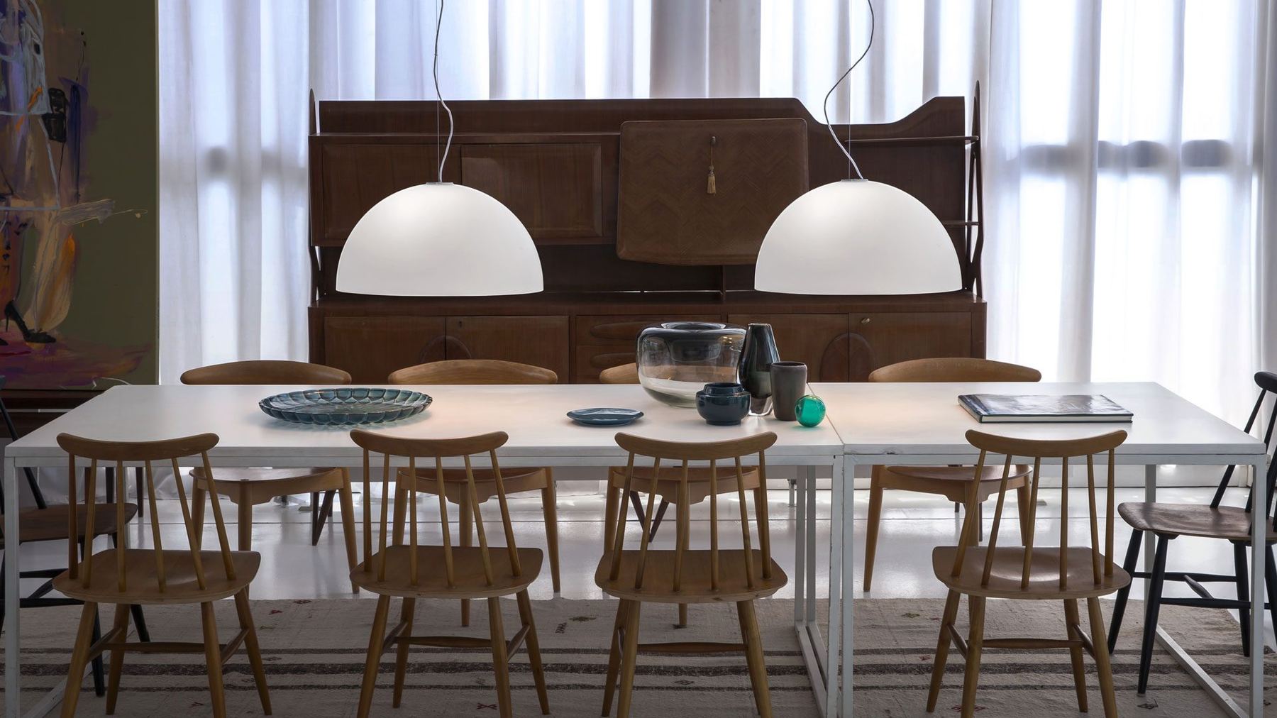 Sala da pranzo con due sospensioni Oluce Sonora sopra il tavolo: la stessa scena al buio e con la luce accesa