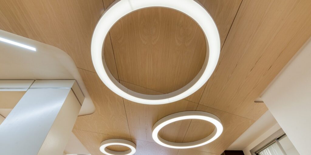 Anelli di luce Panzeri sospesi in un soffitto di legno curvo