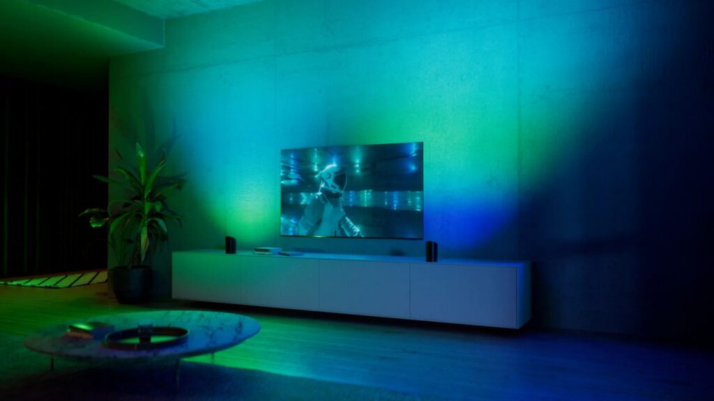 Soggiorno con la TV e le barre di luce Philips Hue Play che colorano la parete