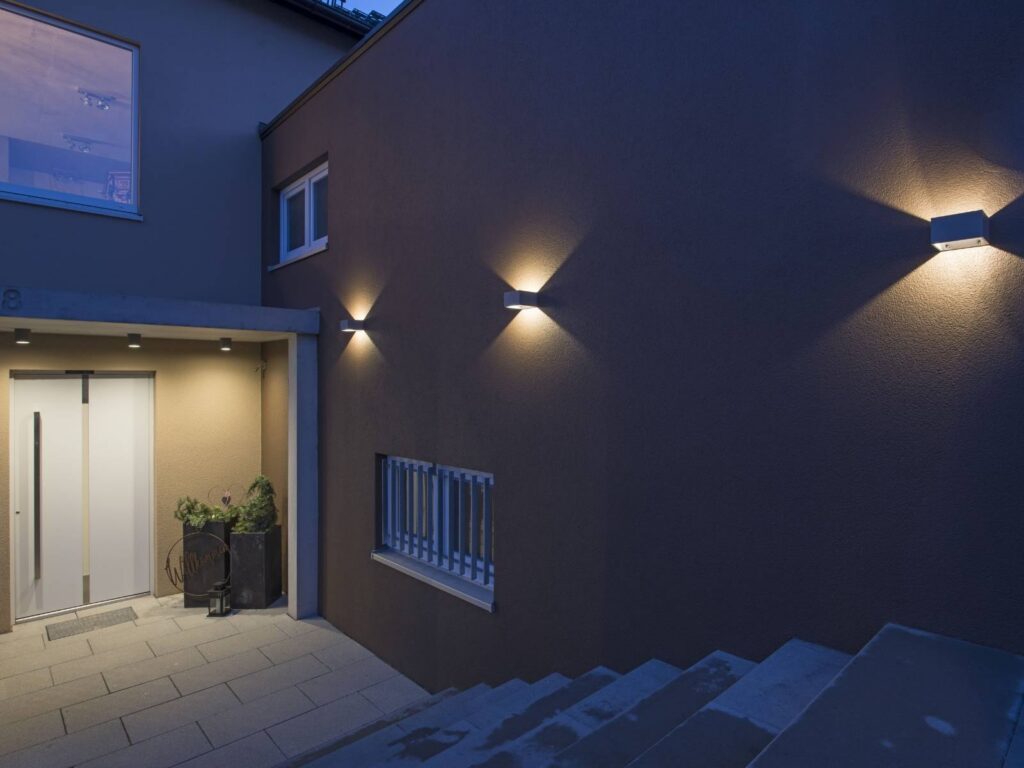 Facciata di casa di sera con le applique SLV che fanno la doppia luce su e giù accanto alla porta