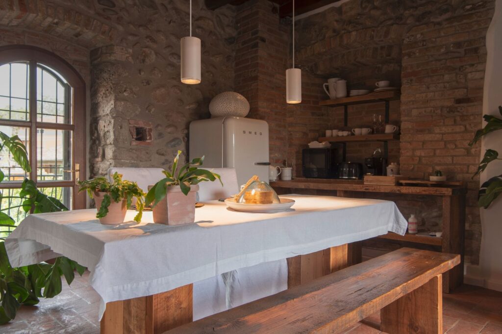Cucina rustica in pietra con il tavolo apparecchiato e le sospensioni SLV NUMINOS sopra