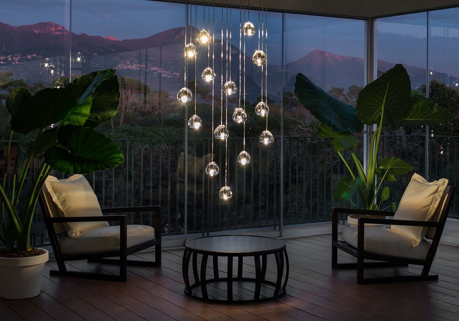Terrazza con vista sulle colline e le gocce di cristallo Terzani Mizu sospese: la stessa scena al buio e con la luce accesa