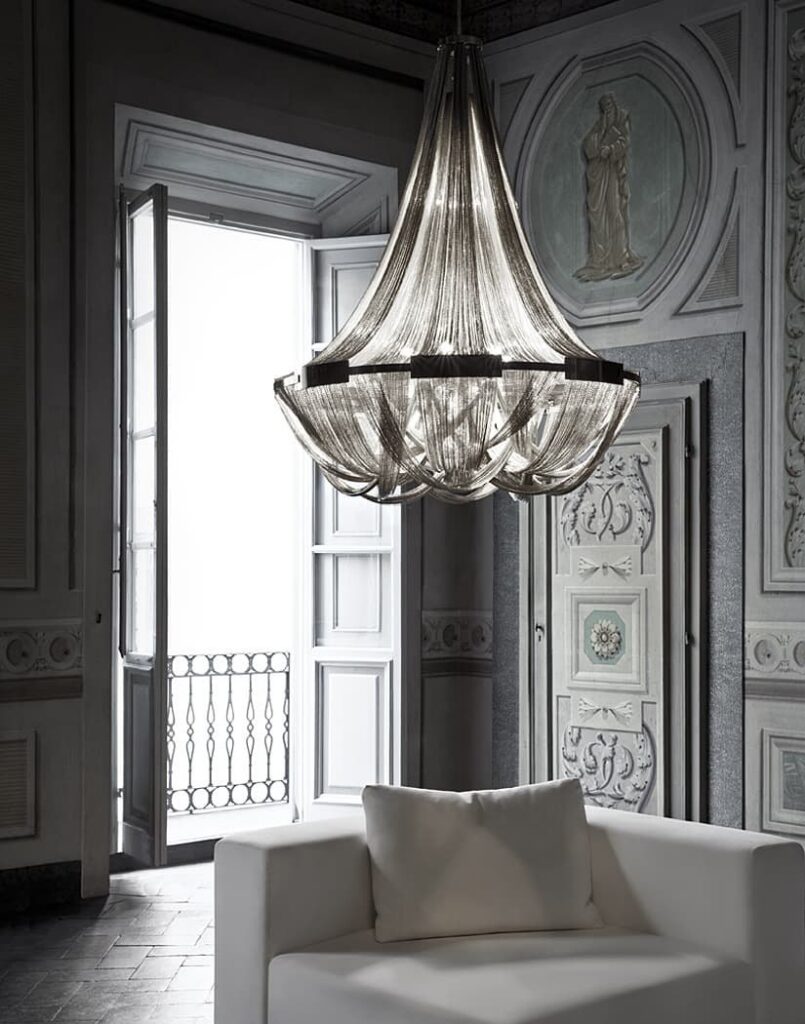 Lampadario Terzani Soscik in catene di alluminio in un salone d'epoca con la poltrona bianca