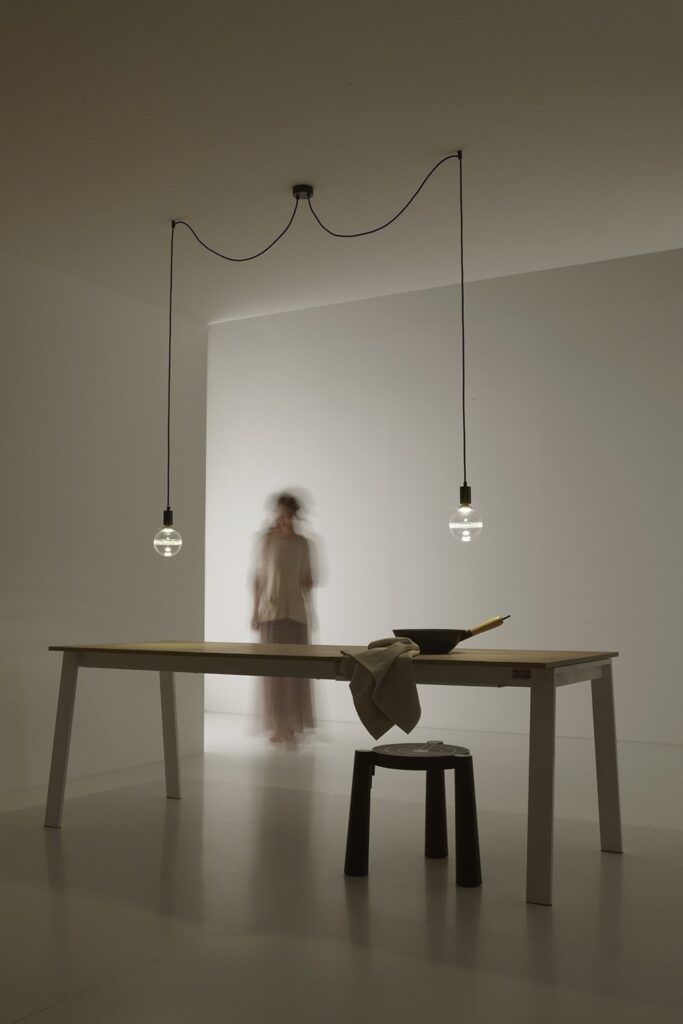 Sospensioni Vesoi Idea con la lampadina sul filo sopra un tavolo, con una persona