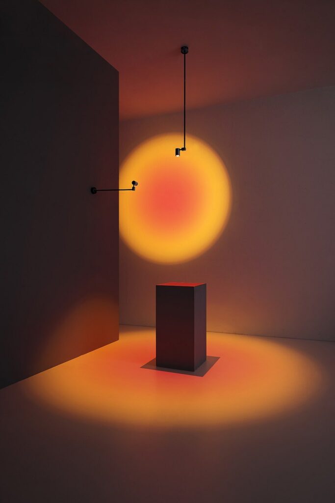 Lampada Vesoi Giotto che proietta un cerchio di luce arancione su una parete