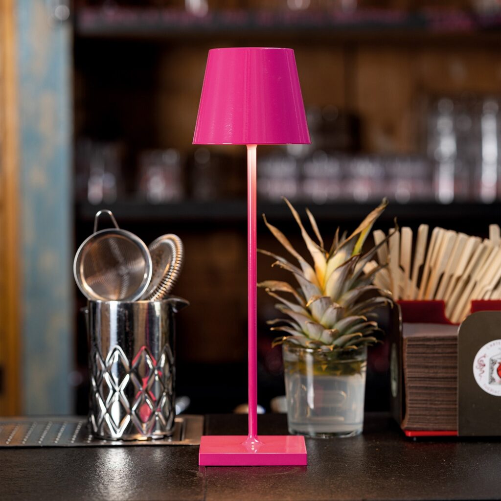 Lampada portatile Zafferano Poldina fucsia sul bancone di un bar