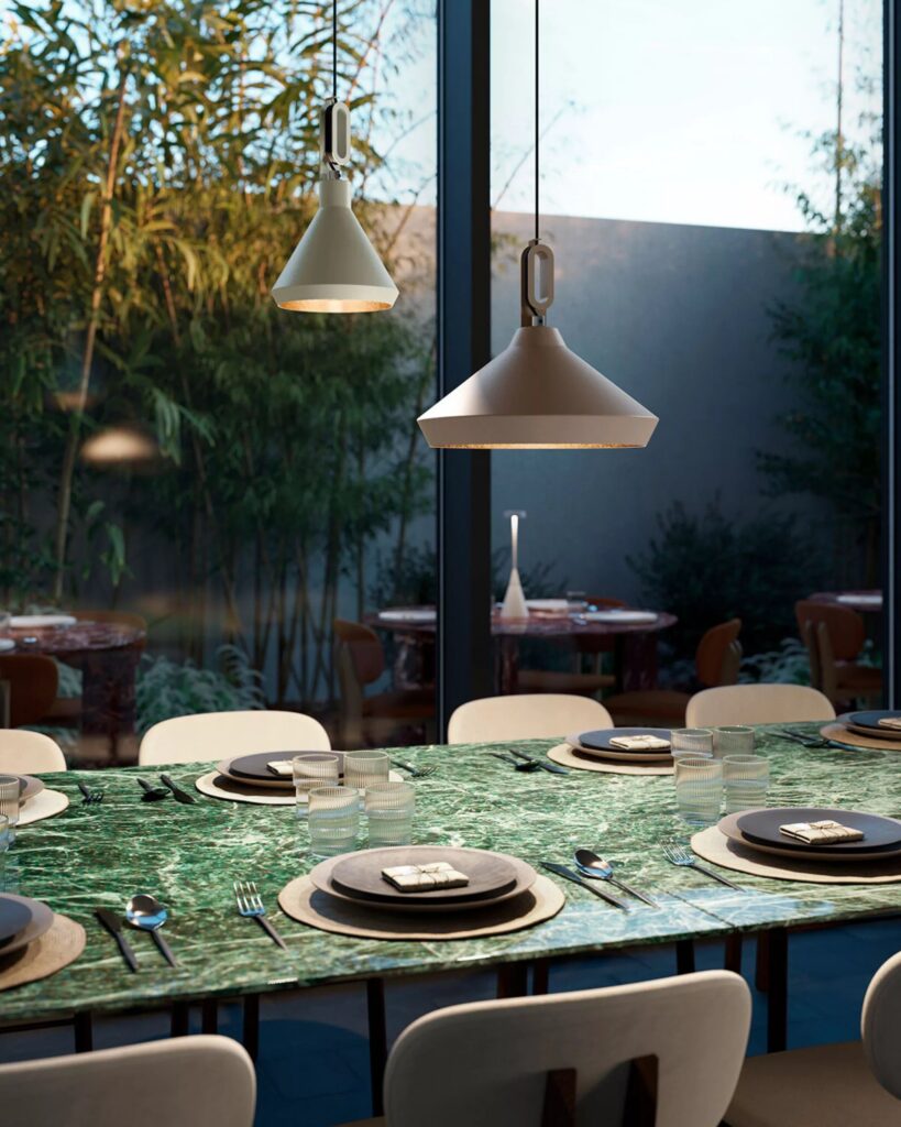 Terrazza con il tavolo apparecchiato e le sospensioni Zava Driyos a campana sopra, con il verde intorno